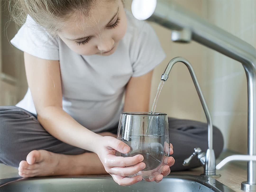 child getting filtered water from faucet