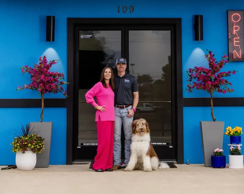 glenn and amber and dog in front of blue Mink building