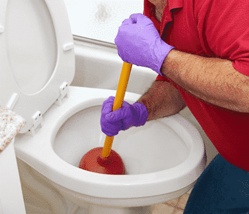 man plunging a clogged toilet