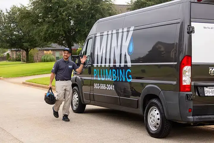 Tech in front of The Mink Plumbing truck in Tyler TX.