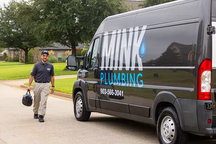 Tech in front of The Mink Plumbing truck in Tyler TX.