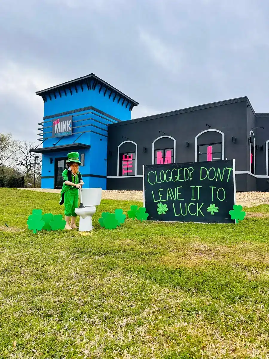 Leprachaun sitting on toilet outside of The Mink Plumbing.