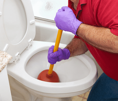 man plunging a clogged toilet